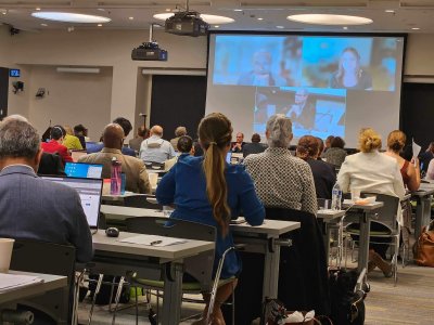 A classroom of people watching a panel discussion.