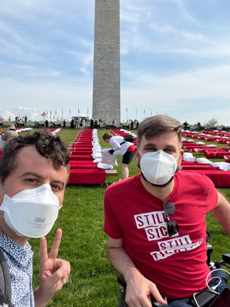 Ben with Adam in front of the Washington Monument with red cots in the background.